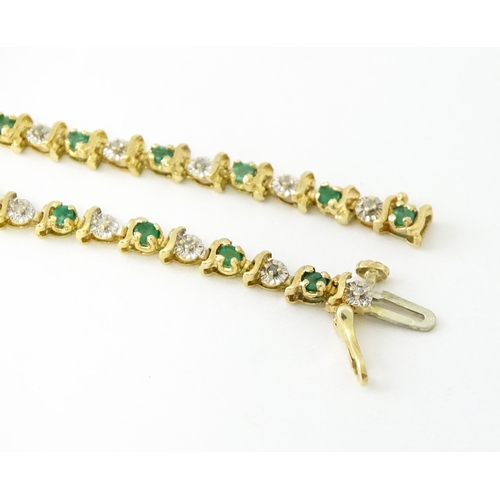 672 - A 9ct gold tennis bracelet set with diamonds and emeralds. Approx. 8