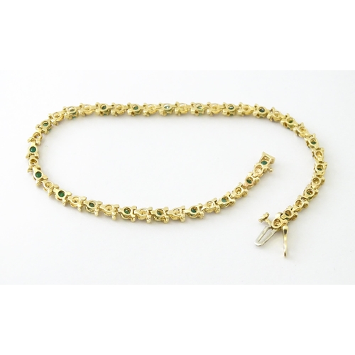 672 - A 9ct gold tennis bracelet set with diamonds and emeralds. Approx. 8