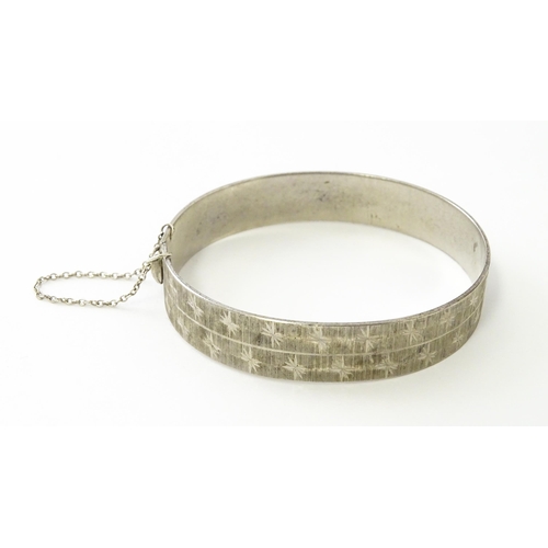 734 - A silver bracelet of bangle form with engraved star decoration hallmarked London 1971, maker MP, and... 