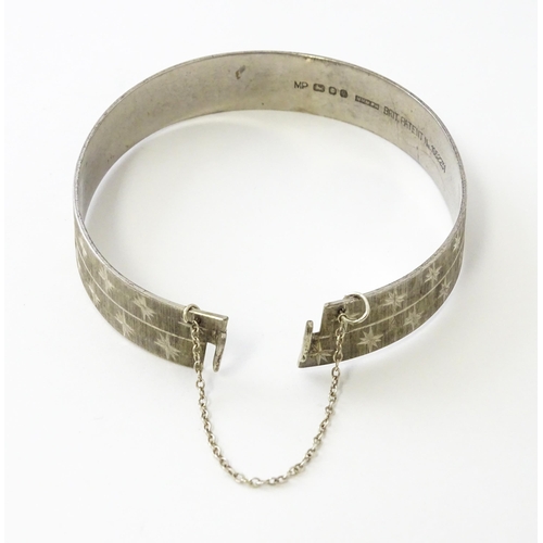 734 - A silver bracelet of bangle form with engraved star decoration hallmarked London 1971, maker MP, and... 