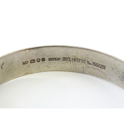 734 - A silver bracelet of bangle form with engraved star decoration hallmarked London 1971, maker MP, and... 