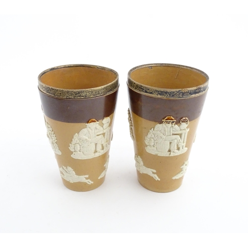 102 - A pair of Royal Doulton two tone stoneware beakers with applied hunting decoration, with silver rims... 