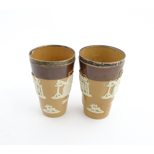 102 - A pair of Royal Doulton two tone stoneware beakers with applied hunting decoration, with silver rims... 