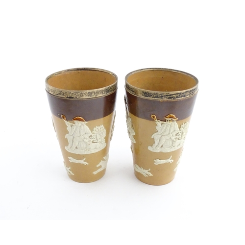 102 - A pair of Royal Doulton two tone stoneware beakers with applied hunting decoration, with silver rims... 