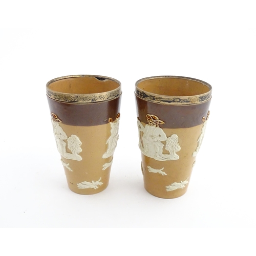 102 - A pair of Royal Doulton two tone stoneware beakers with applied hunting decoration, with silver rims... 