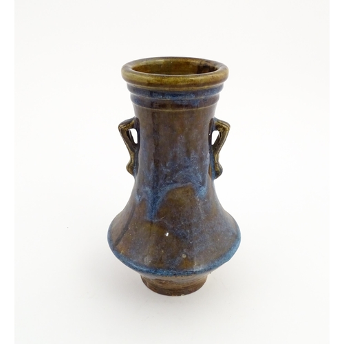 32 - An Oriental twin handled vase with a high fired glaze and banded detail to rim. Approx. 11 14/