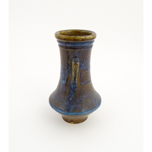 32 - An Oriental twin handled vase with a high fired glaze and banded detail to rim. Approx. 11 14/