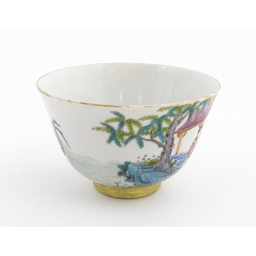 41 - A Chinese famille rose tea bowl decorated with figures in a river landscape. Character marks under. ... 