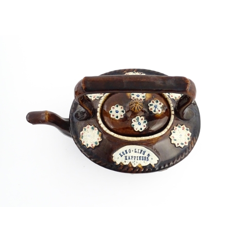 56 - A Victorian Measham bargeware teapot with applied floral and foliate motifs and motto Long Life & Ha... 