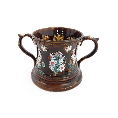 57 - A Victorian Measham bargeware frog loving cup decorated with birds and flowers, the interior with fo... 