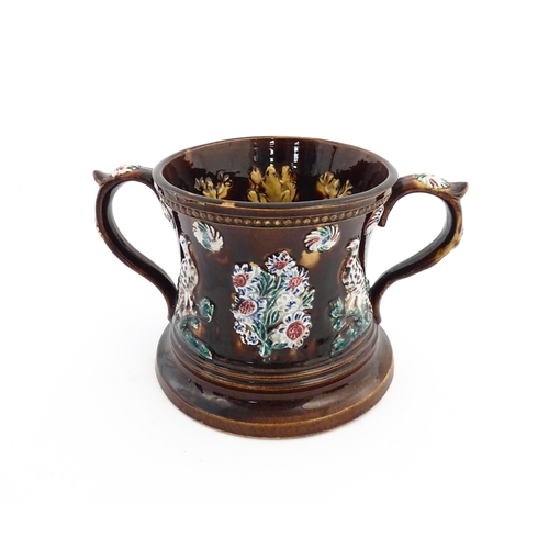 57 - A Victorian Measham bargeware frog loving cup decorated with birds and flowers, the interior with fo... 