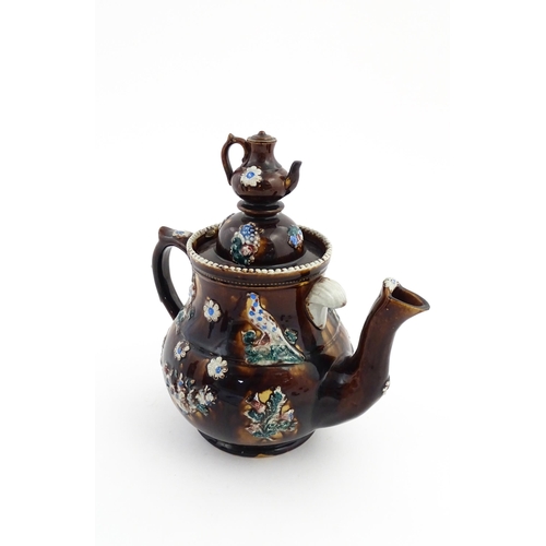 58 - A large Victorian Measham bargeware teapot with a teapot finial to lid, the body decorated with flow... 