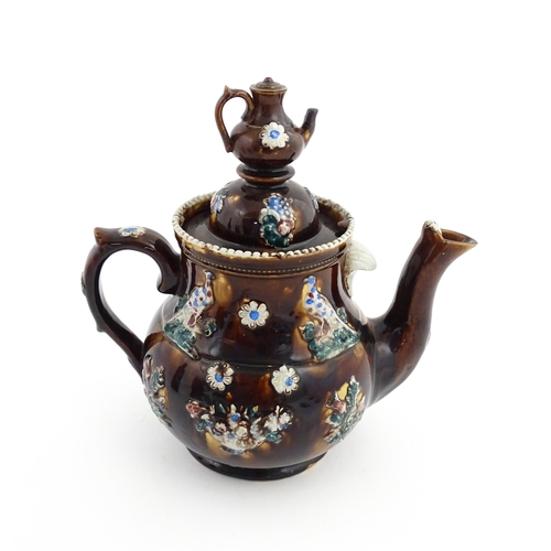 58 - A large Victorian Measham bargeware teapot with a teapot finial to lid, the body decorated with flow... 