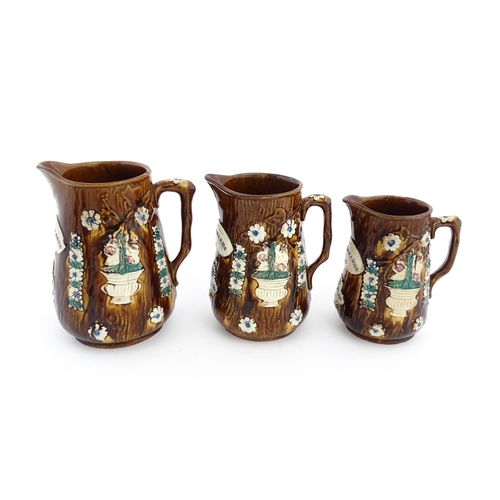 59 - A set of three Victorian Measham bargeware graduated jugs decorated with flowers and foliage, each b... 