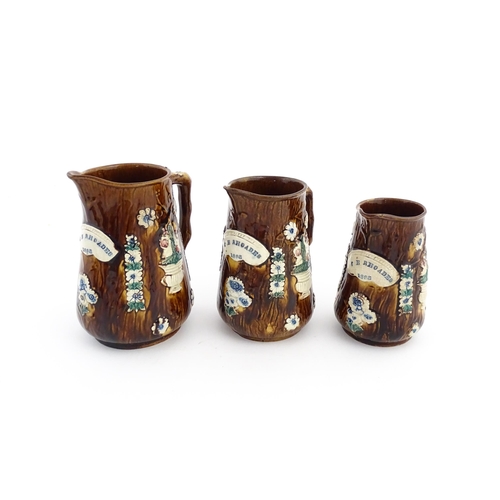 59 - A set of three Victorian Measham bargeware graduated jugs decorated with flowers and foliage, each b... 