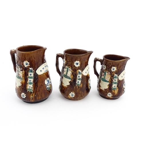 59 - A set of three Victorian Measham bargeware graduated jugs decorated with flowers and foliage, each b... 