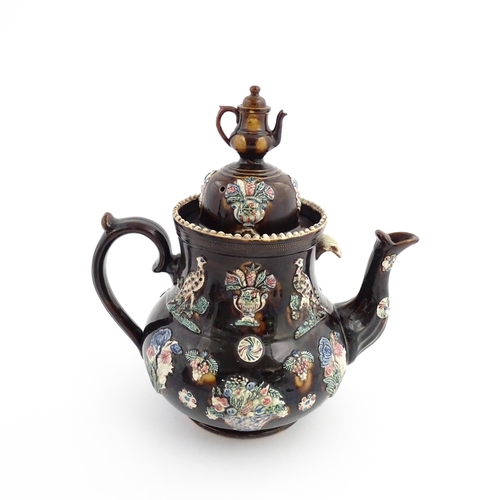 61 - A large Victorian Measham bargeware teapot, the lid with teapot finial, the body decorated with appl... 