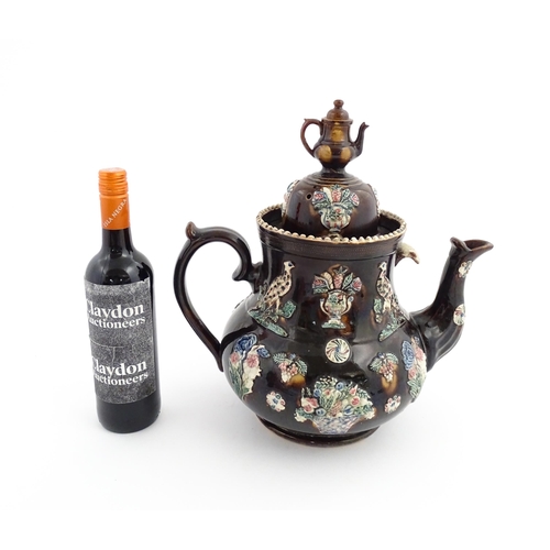 61 - A large Victorian Measham bargeware teapot, the lid with teapot finial, the body decorated with appl... 