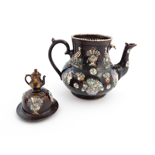 61 - A large Victorian Measham bargeware teapot, the lid with teapot finial, the body decorated with appl... 