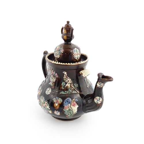 61 - A large Victorian Measham bargeware teapot, the lid with teapot finial, the body decorated with appl... 