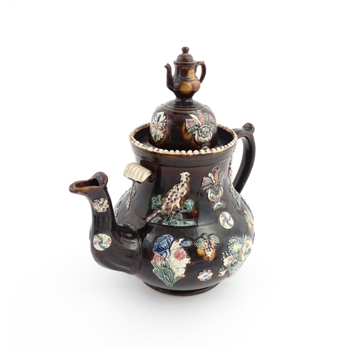 61 - A large Victorian Measham bargeware teapot, the lid with teapot finial, the body decorated with appl... 