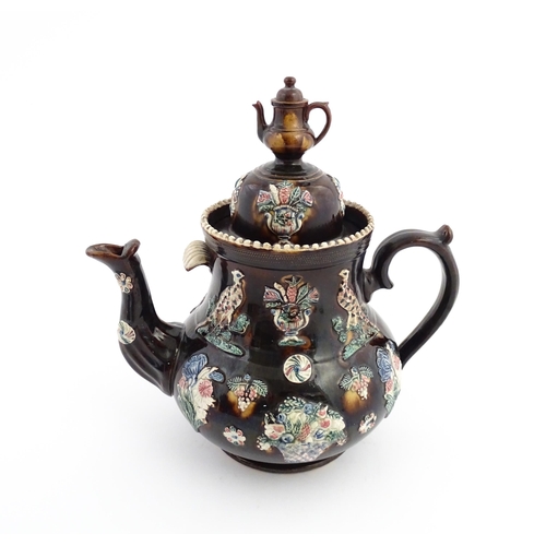 61 - A large Victorian Measham bargeware teapot, the lid with teapot finial, the body decorated with appl... 