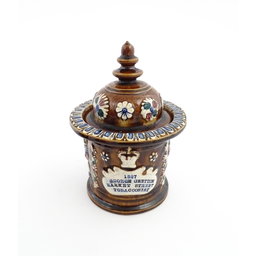 62 - A Victorian Measham bargeware advertising tobacco jar and tamper decorated with flowers and foliage ... 