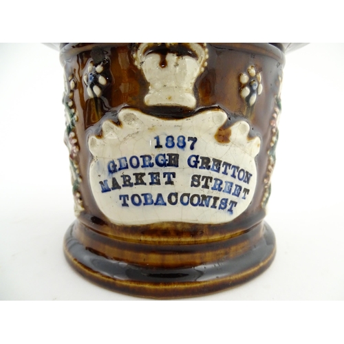 62 - A Victorian Measham bargeware advertising tobacco jar and tamper decorated with flowers and foliage ... 