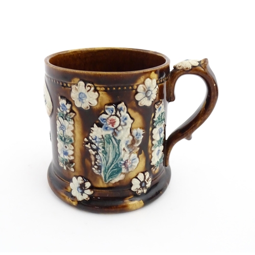 66 - A Victorian Measham bargeware mug decorated with flower, thistles, foliage and a plaque titled James... 