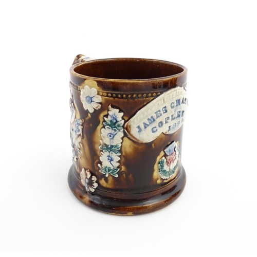 66 - A Victorian Measham bargeware mug decorated with flower, thistles, foliage and a plaque titled James... 