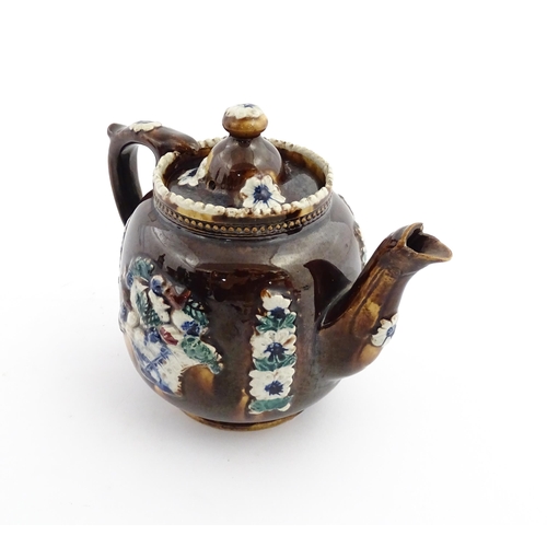 68 - A Victorian Measham bargeware teapot decorated with flowers, a profile portrait and a plaque surmoun... 