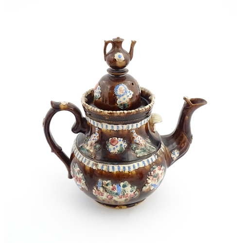 73 - A large George III Measham bargeware teapot, with teapot finial to lid, the body decorated with flow... 