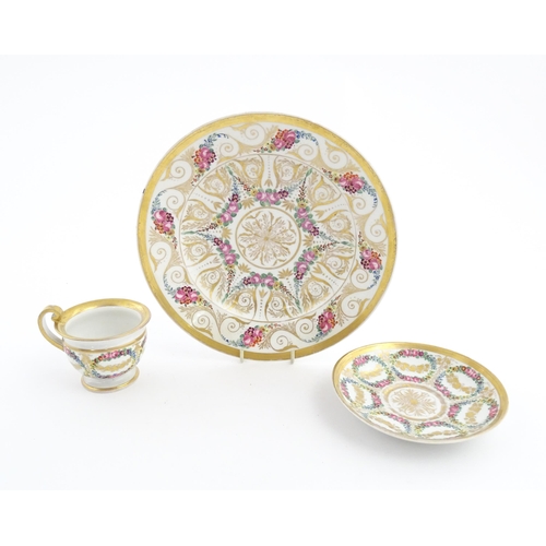 126 - A 19thC hand painted plate, cup and saucer decorated with floral swags and gilt scrolls. The plate i... 