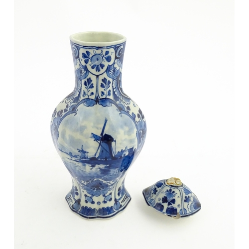 129 - A Dutch Royal Delft blue and white vase and cover decorated with flowers, foliage and a windmill sce... 