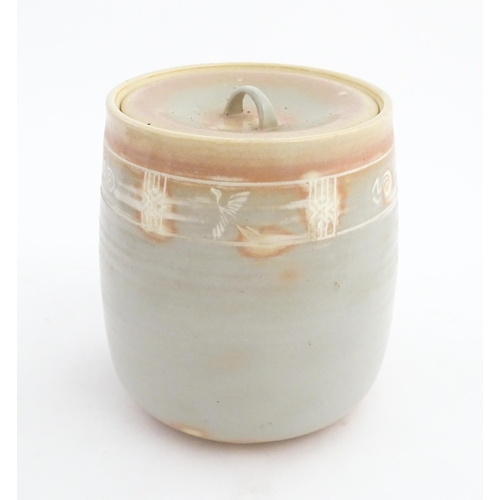 190 - A studio pottery biscuit barrel / jar with pink and grey glaze and incised banded decoration. Approx... 