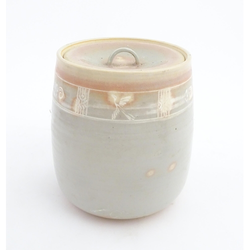 190 - A studio pottery biscuit barrel / jar with pink and grey glaze and incised banded decoration. Approx... 