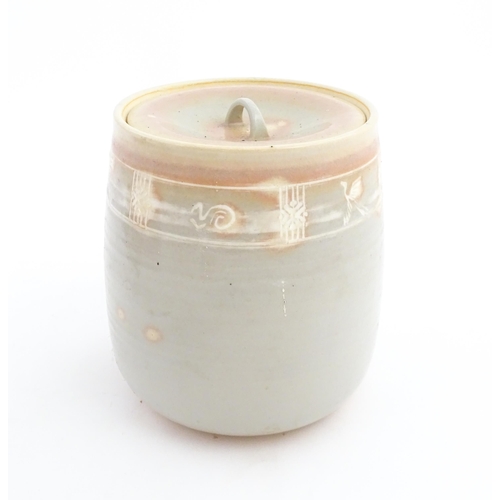 190 - A studio pottery biscuit barrel / jar with pink and grey glaze and incised banded decoration. Approx... 