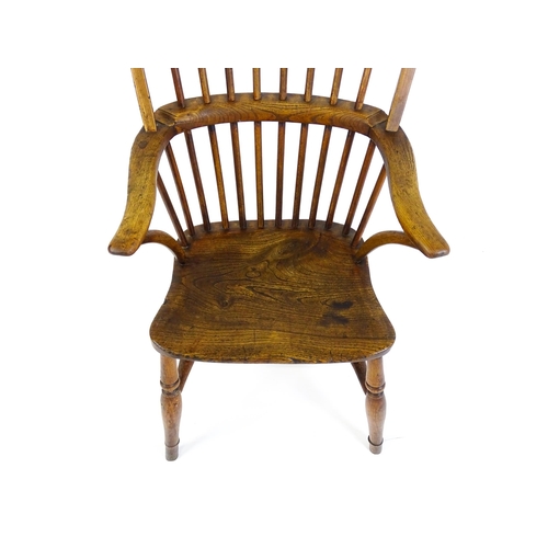 1441 - A 19thC double bow back Windsor chair with a shaped elm seat and raised on four turned tapering legs... 