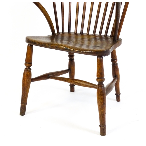 1441 - A 19thC double bow back Windsor chair with a shaped elm seat and raised on four turned tapering legs... 