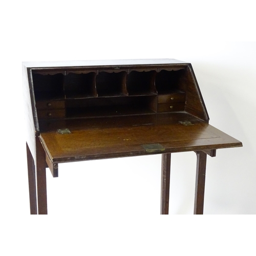 1562 - A late 18thC oak clerks desk with a fall front above two short drawers with swan neck handles and ra... 