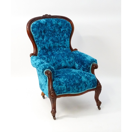 1566 - A Victorian mahogany armchair with a carved cresting rail and deep buttoned backrest above a sprung ... 