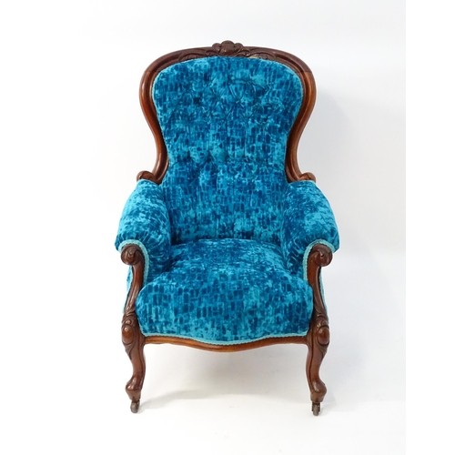 1566 - A Victorian mahogany armchair with a carved cresting rail and deep buttoned backrest above a sprung ... 