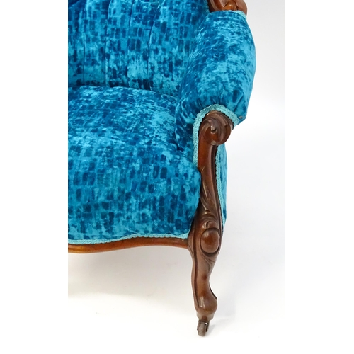 1566 - A Victorian mahogany armchair with a carved cresting rail and deep buttoned backrest above a sprung ... 