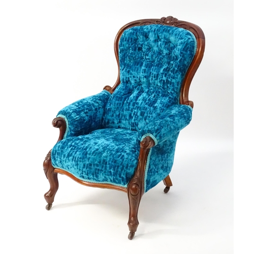 1566 - A Victorian mahogany armchair with a carved cresting rail and deep buttoned backrest above a sprung ... 