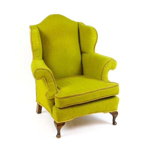 1568 - An Edwardian wingback armchair with scrolled arms and raised on short cabriole legs terminating in p... 