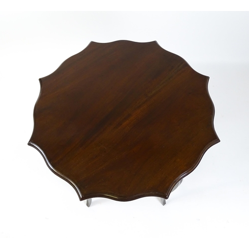 1635 - An Edwardian mahogany occasional table with a shaped, moulded top above four cabriole legs united by... 