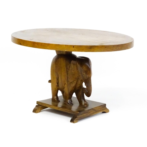 1639 - A mid 20thC teak occasional table with an oval top above an elephant formed pedestal and rectangular... 