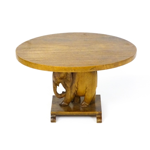 1639 - A mid 20thC teak occasional table with an oval top above an elephant formed pedestal and rectangular... 