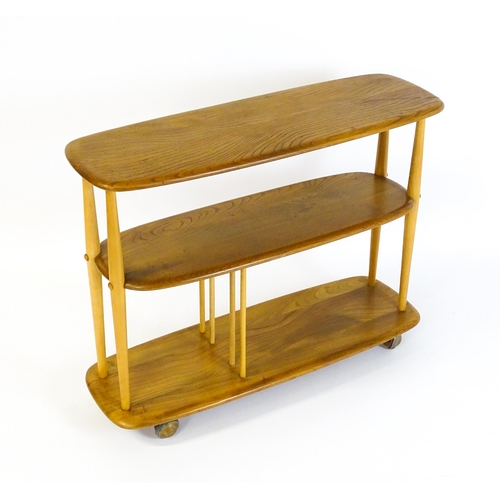 1650 - Vintage / Retro: An Ercol elm trolley with three shaped tiers on four turned supports and raised on ... 