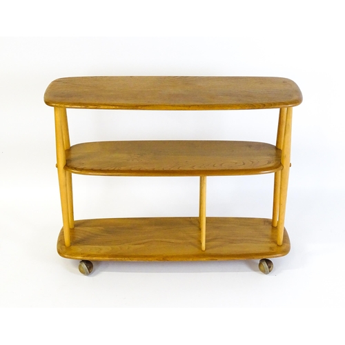 1650 - Vintage / Retro: An Ercol elm trolley with three shaped tiers on four turned supports and raised on ... 